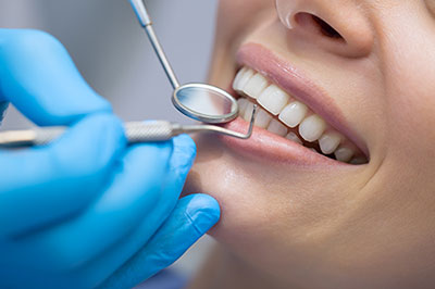 The image shows a dental professional performing dental work on a patient, with the patient s mouth open and the professional using a dental tool.