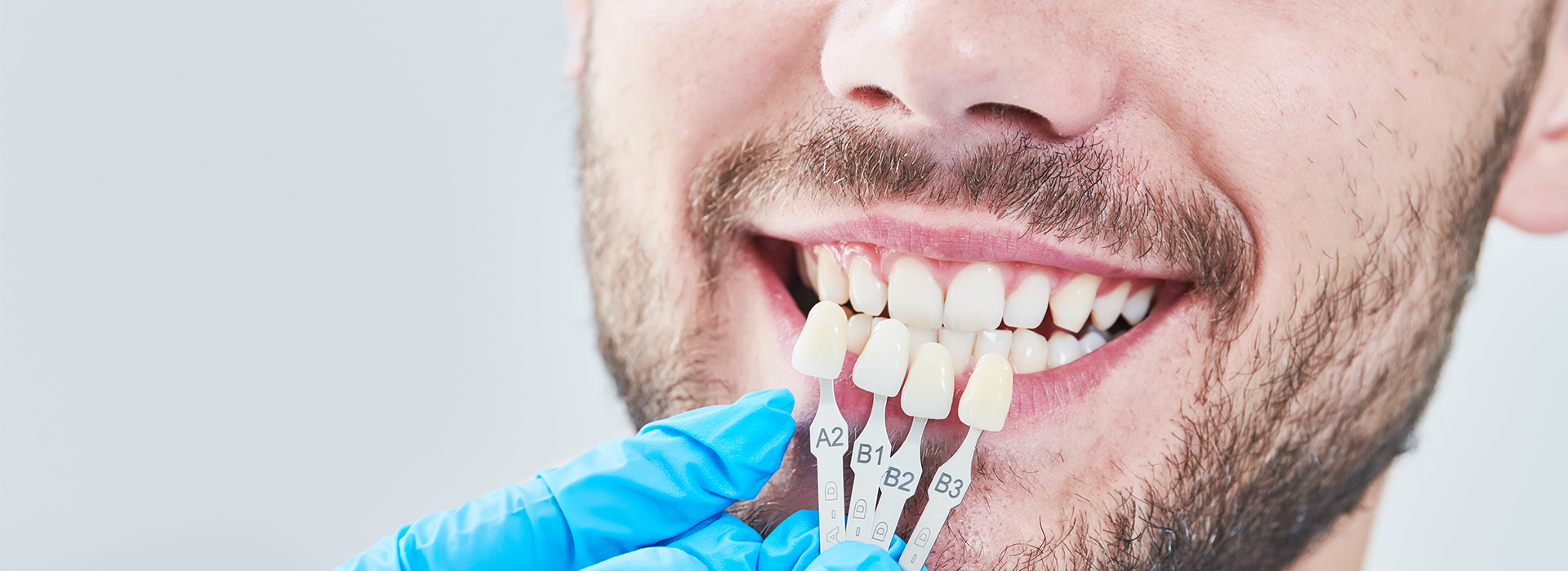 The image shows a man smiling with his teeth, wearing a blue surgical mask and holding a toothbrush with toothpaste.